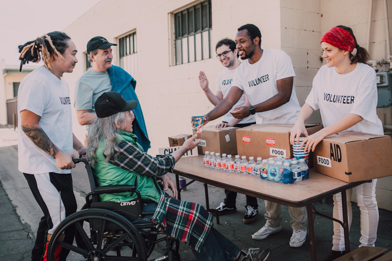 our-services-2 Volunteers distribute bottled water and supplies to diverse individuals in an outdoor setting, showcasing community support.