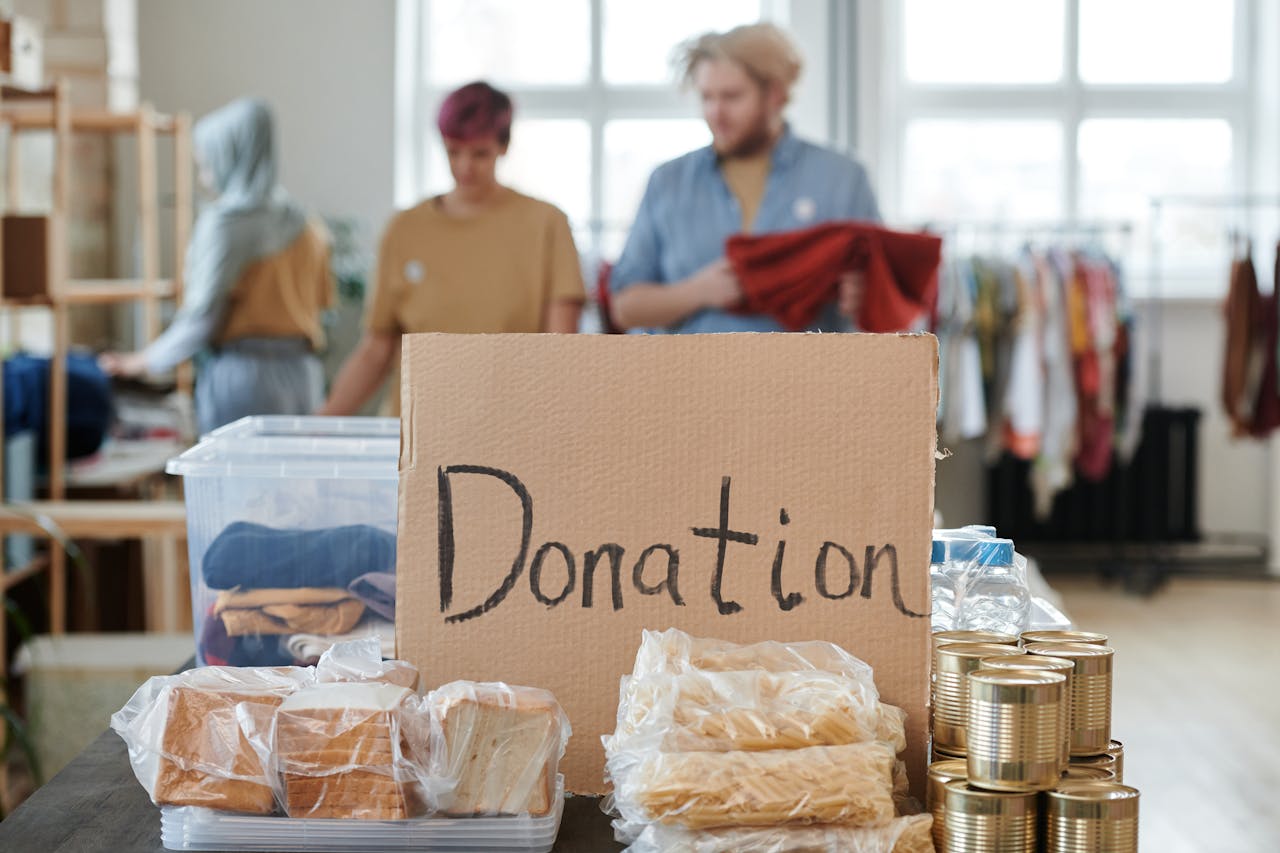 gallery-3 Volunteers sort clothes and food in a donation center. Cardboard sign reads 'Donation.'