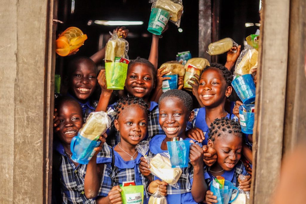 Group of happy children holding food packages and smiling outdoors.